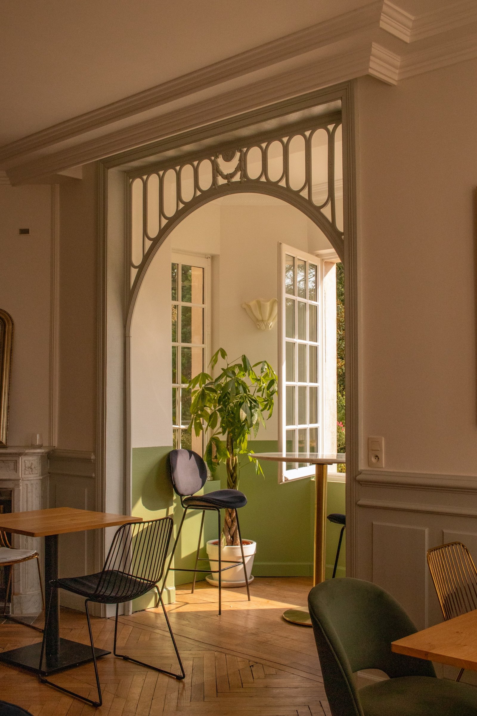 Arche décorative historique encadrant une fenêtre ouverte et des murs vert tendre
