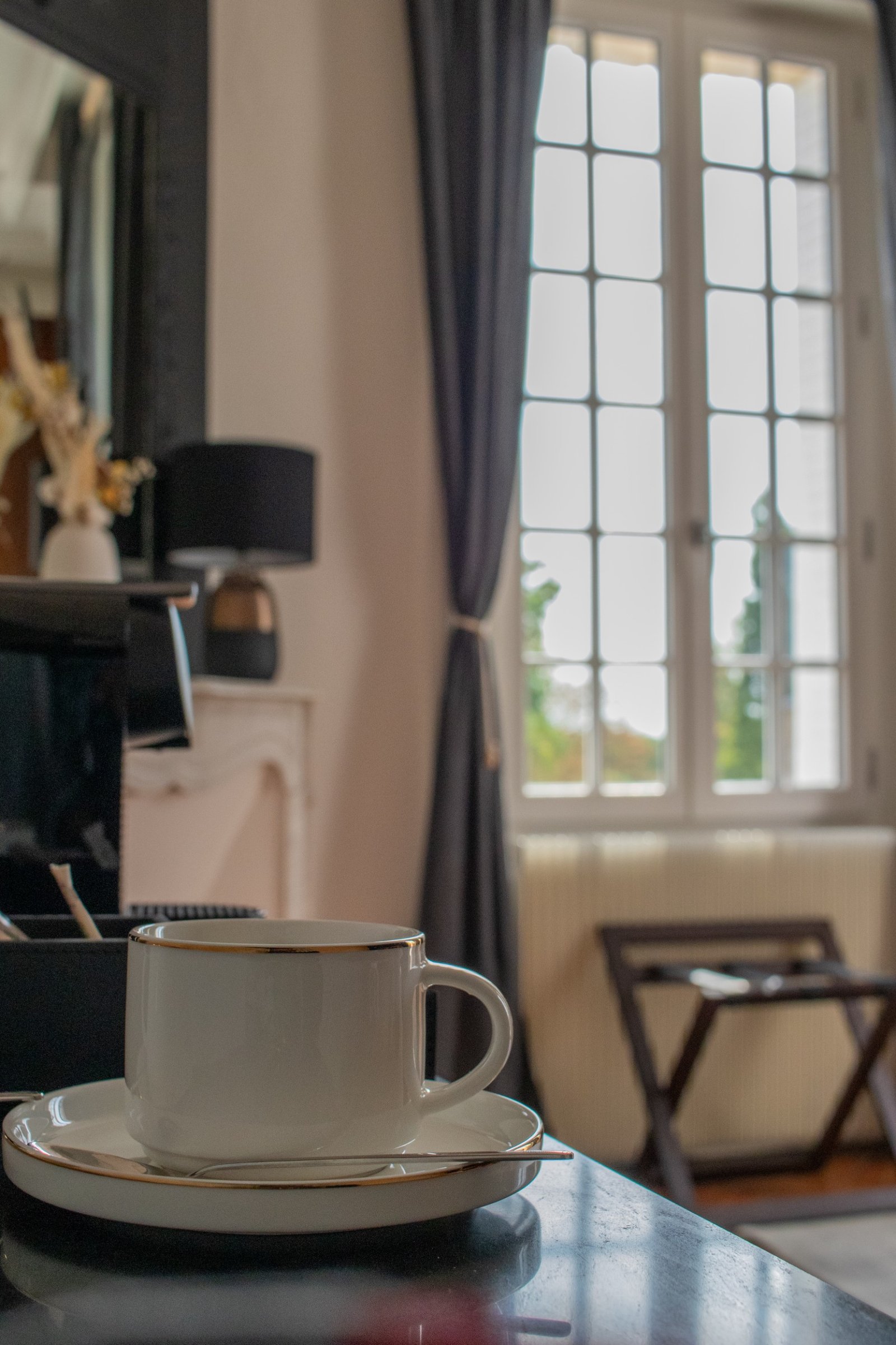Tasse de café au liseré doré posée dans une pièce à la lumière douce