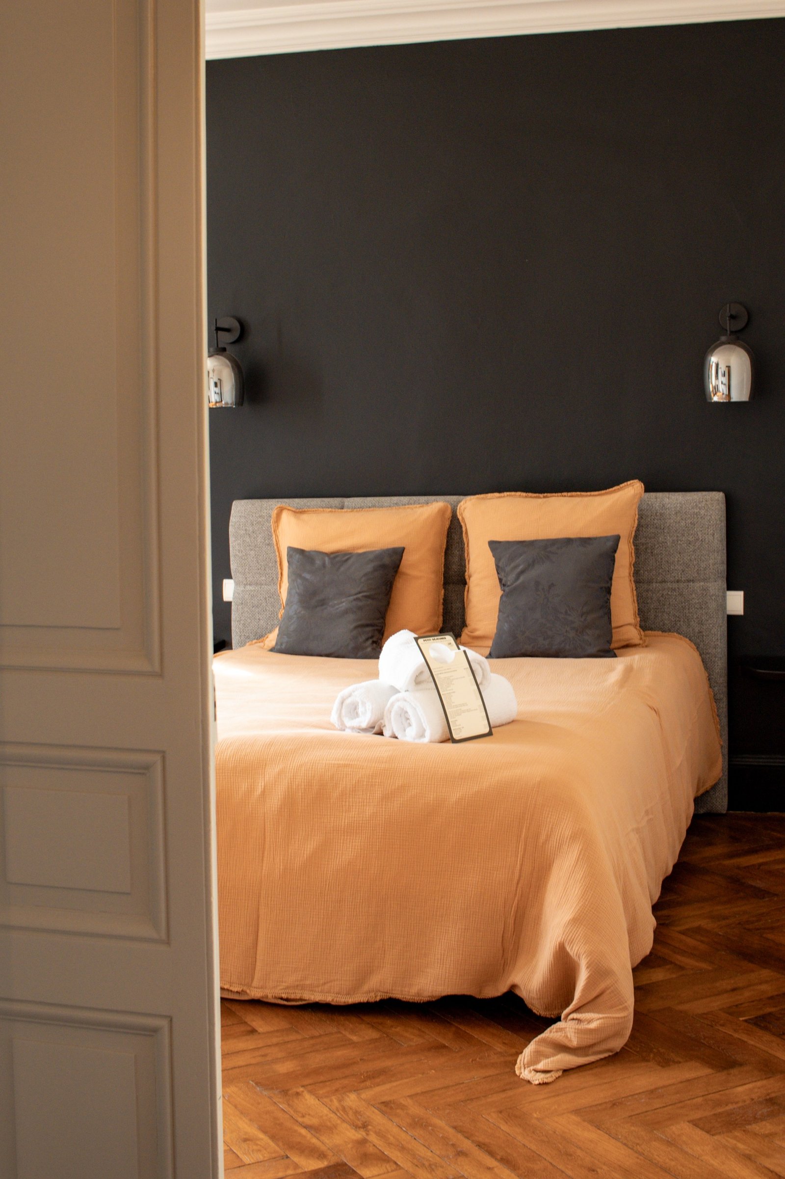Chambre chaleureuse au linge terracotta, vue à travers une porte entrouverte